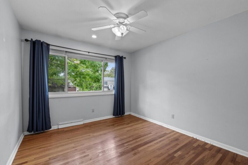 Bedroom 3, with light gray walls, wood floor, and ceiling fan.