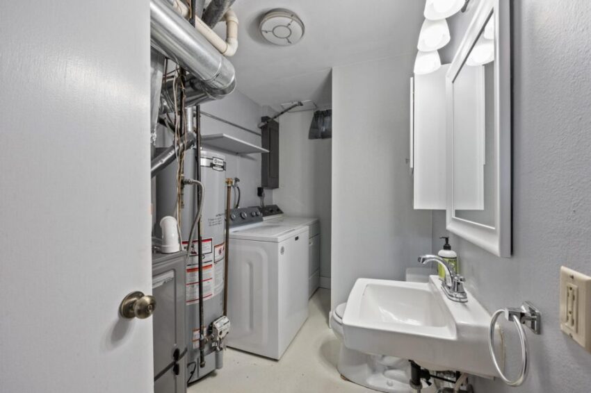 Lower level bathroom and utility area with washer and dryer and hot water heater.