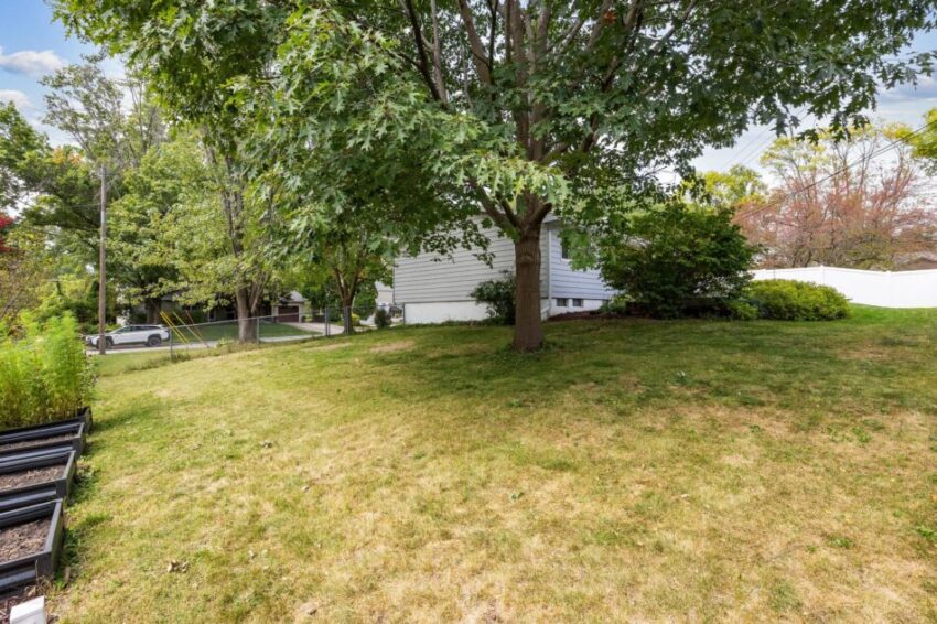 House from a distance with grassy lawn and mature tree.