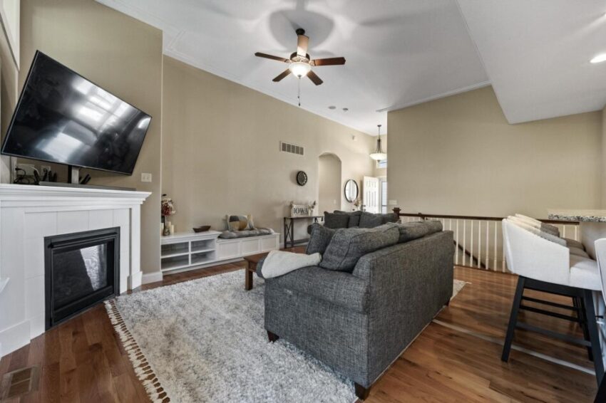 Living room with staircase leading to lower level and stools at breakfast bar.