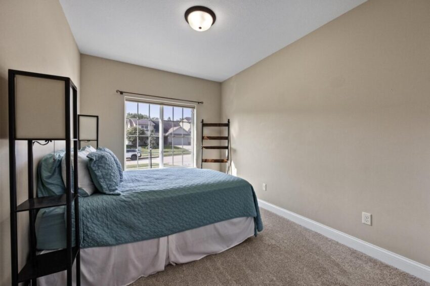 Second bedroom, with beige walls, light fixture, and white trim.