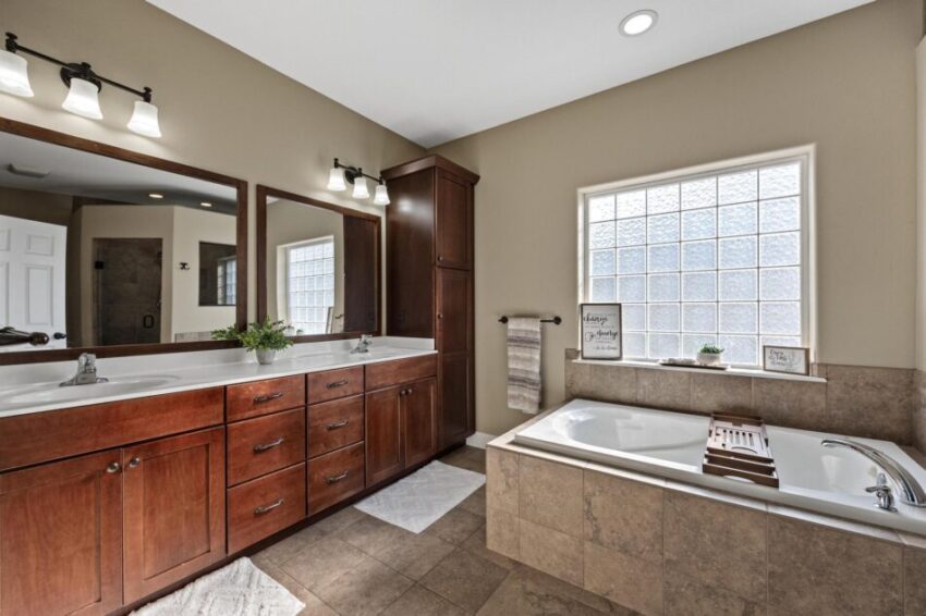 Primary bath, with tiled tub and frosted glass windows and two sinks.