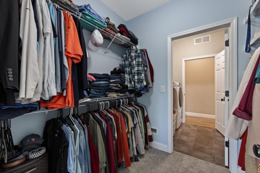 Walkiin closet with storage racks and carpeted floor.