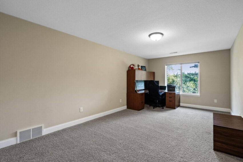Lower level with beige walls, white trim, and ceiling lights.