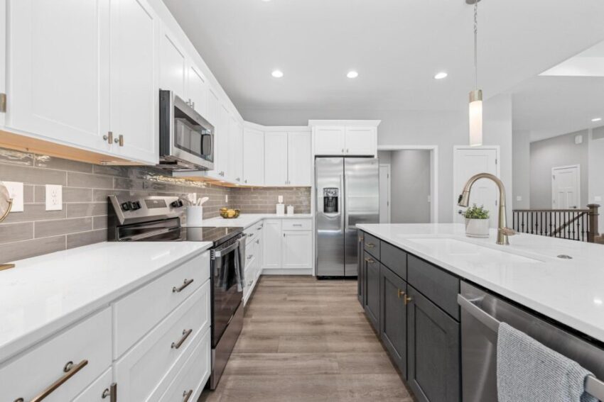Kitchen with quartz countertops, white cabinetry, and dark island.