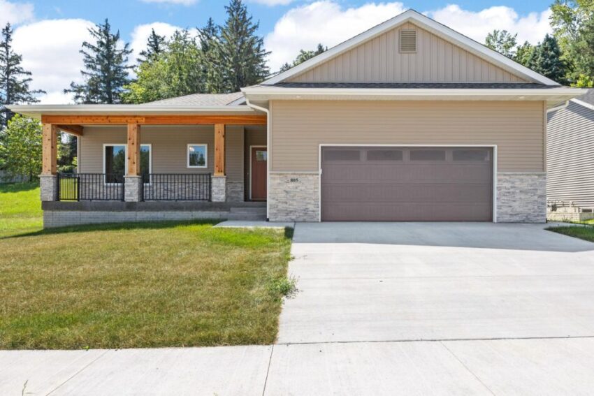 Ranch home with two-car garage and front porch with pillars and railing.