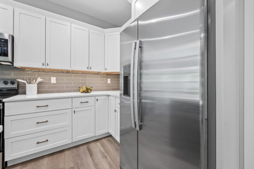 Kitchen with stainless fridge and tan backsplash.