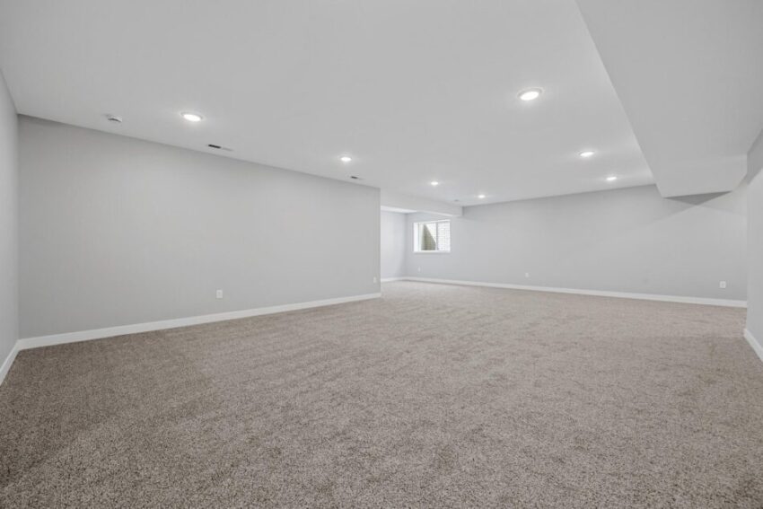 Spacious lower level with built-in lights and white trim.