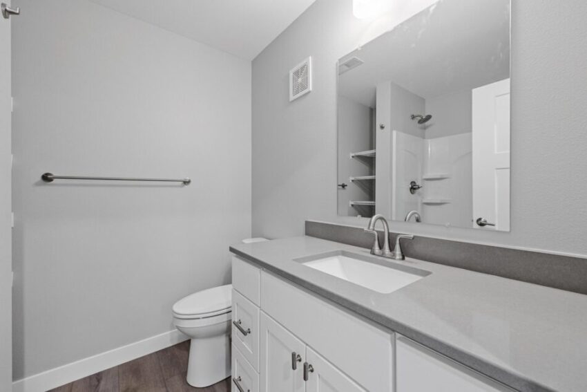 Bathroom 3, with gray counter, bath shower combo, and white cabinet.