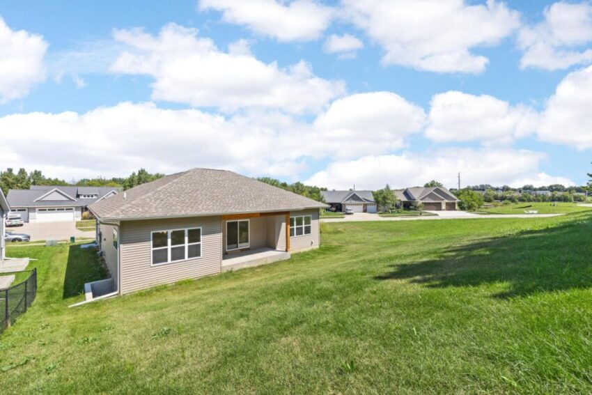 View of home surrounded by lawn from slope above the back.