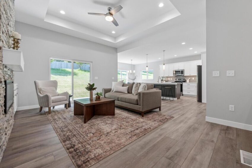 Living room with ceiling fan, vinyl flooring, and large walk-out glass doors.