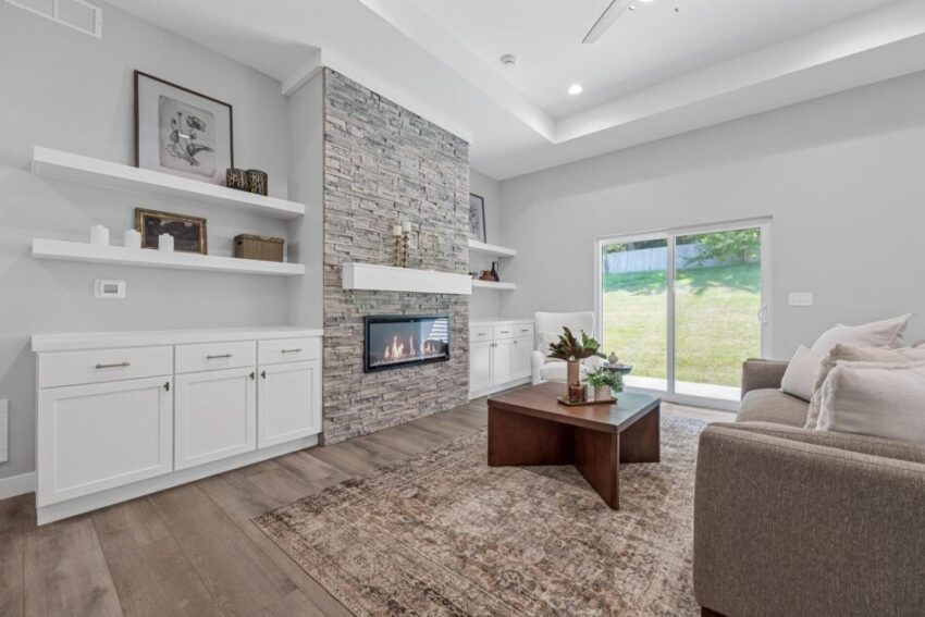 Living room with built-in fireplace surrounded by stone and white mantle.