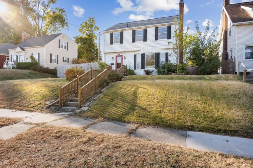 White two-story home with red door and dark shutters.