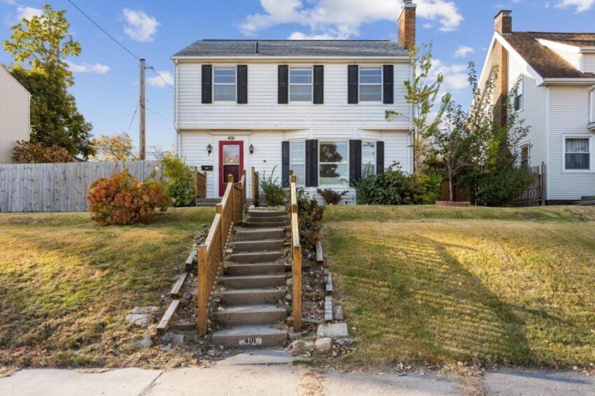 Two-story house with stairs leading up to the front door.