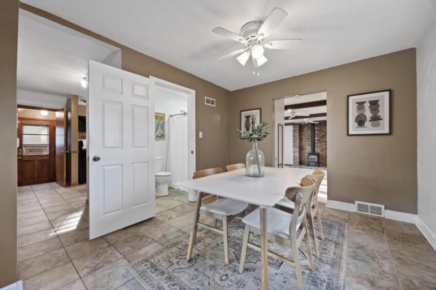 Dining room with ceiling fan, tan walls, and white trim.