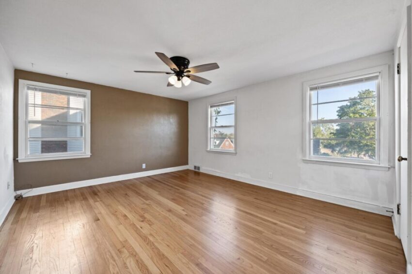 Bedroom 1, with hardwood floors, accent wall, and ceiling fan.