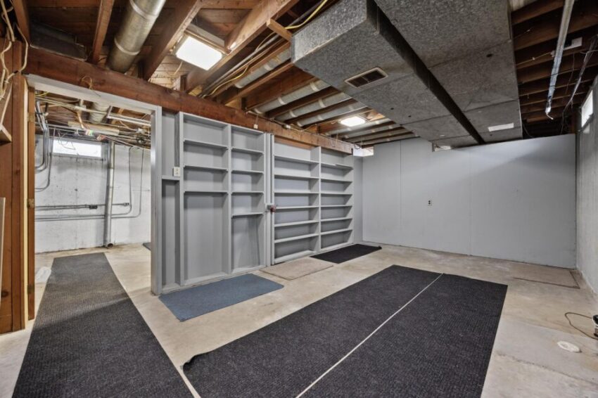 Unfinished basement with built in shelving and concrete floor.