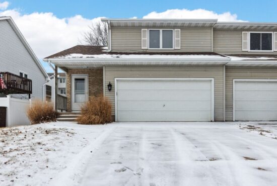 Zero lot home with a two car garage and wide concrete driveway.