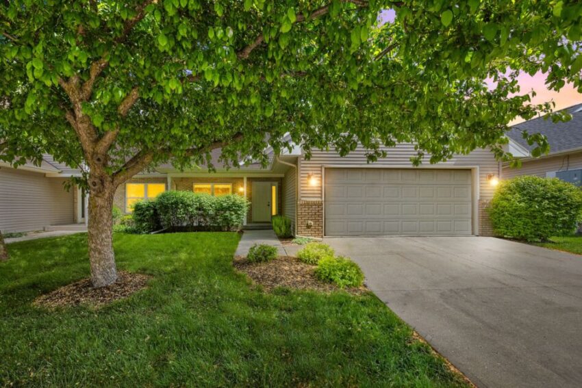 House with a two-car garage and a tree in the front yard.