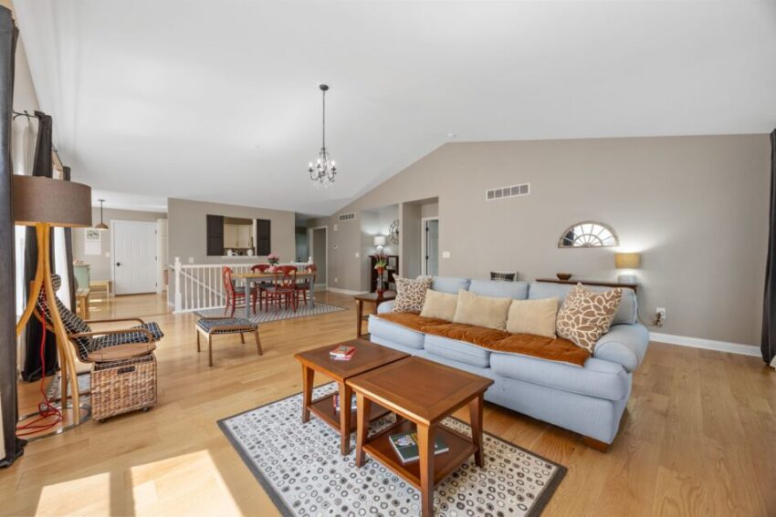 Spacious living room with blue sofa, wooden table, and dining area.