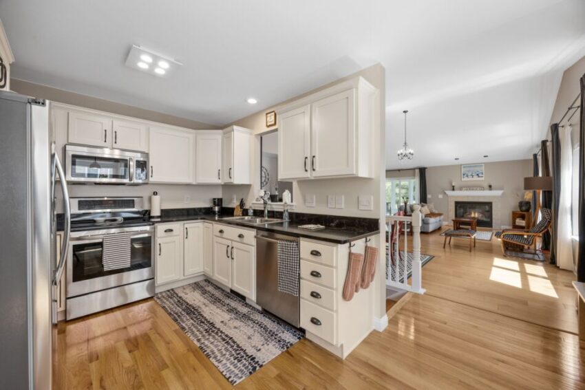 Modern kitchen with white cabinets, stainless steel appliances, and hardwood floors.