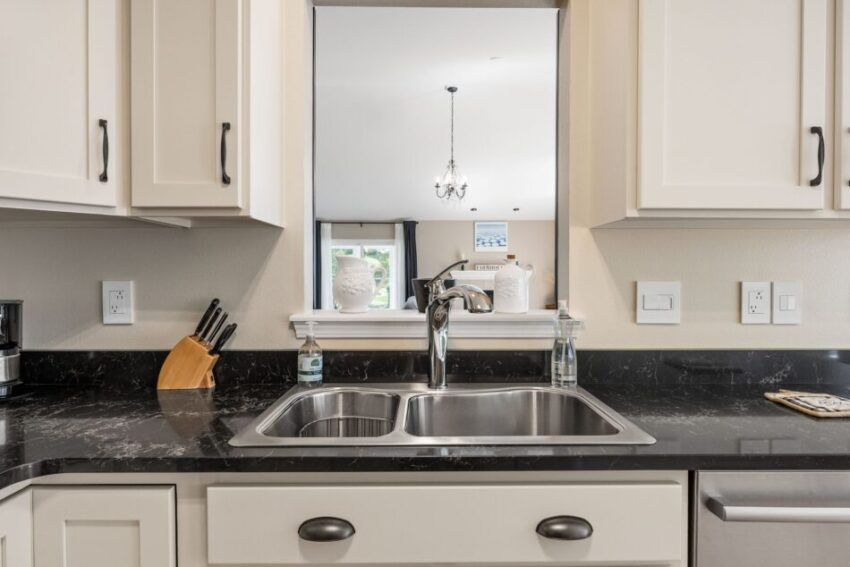 Modern kitchen with black countertop, white cabinets, and stainless steel sink.