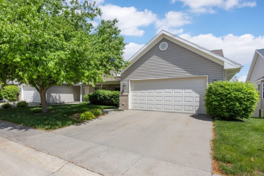 Suburban house with a two-car garage and a tree in the front yard.