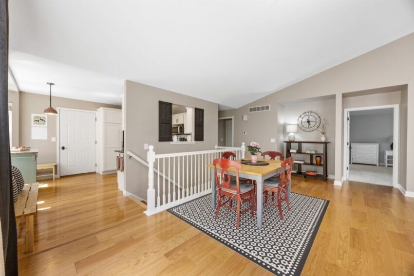 Dining area with wooden floor, red chairs, and patterned rug.
