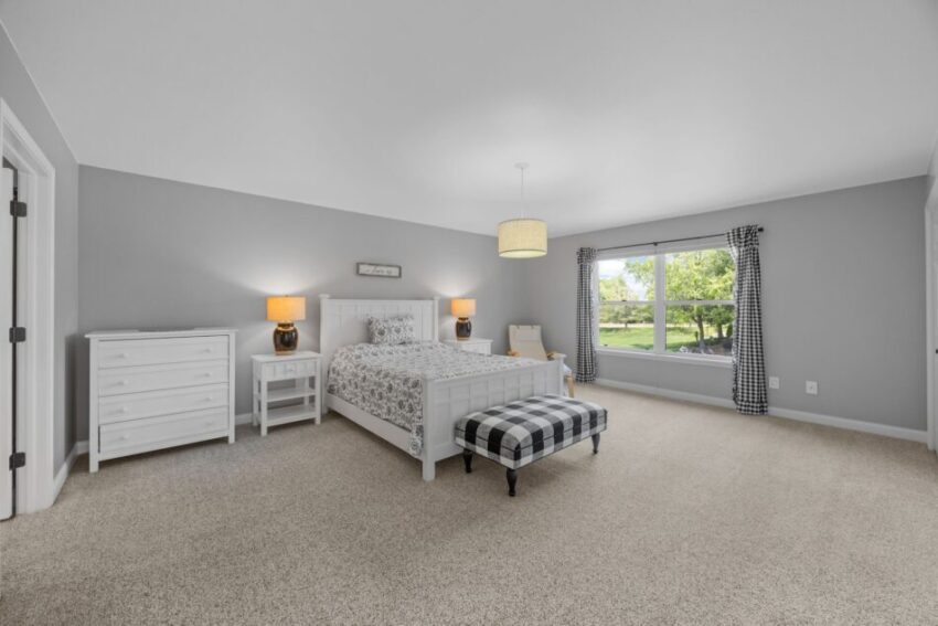 Spacious bedroom with gray walls, white furniture, and large window.