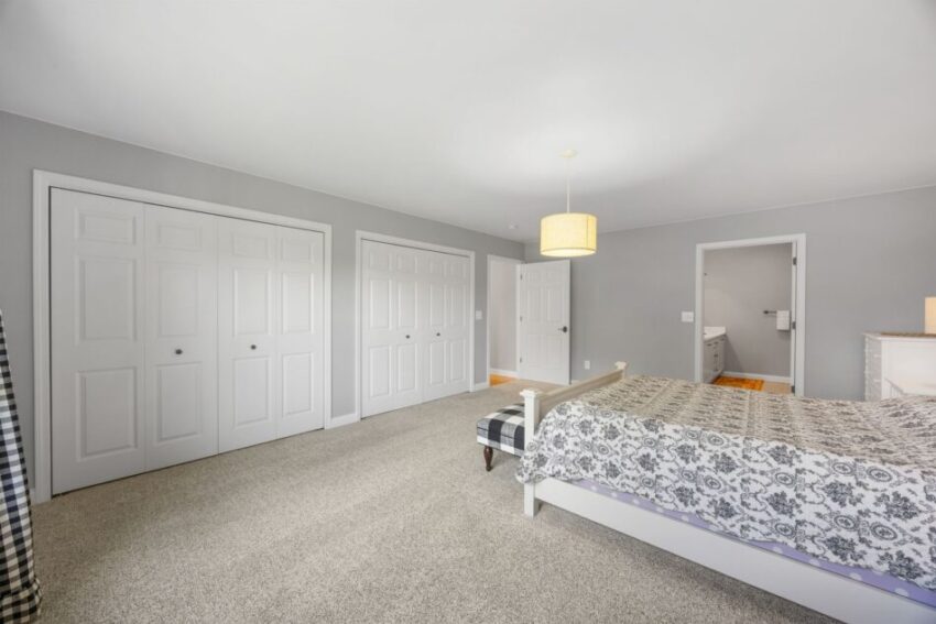 Spacious bedroom with gray walls, patterned bedspread, and large closets.