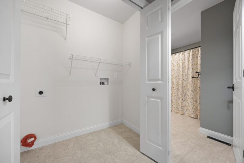 Empty laundry room with open doors and wire shelves.