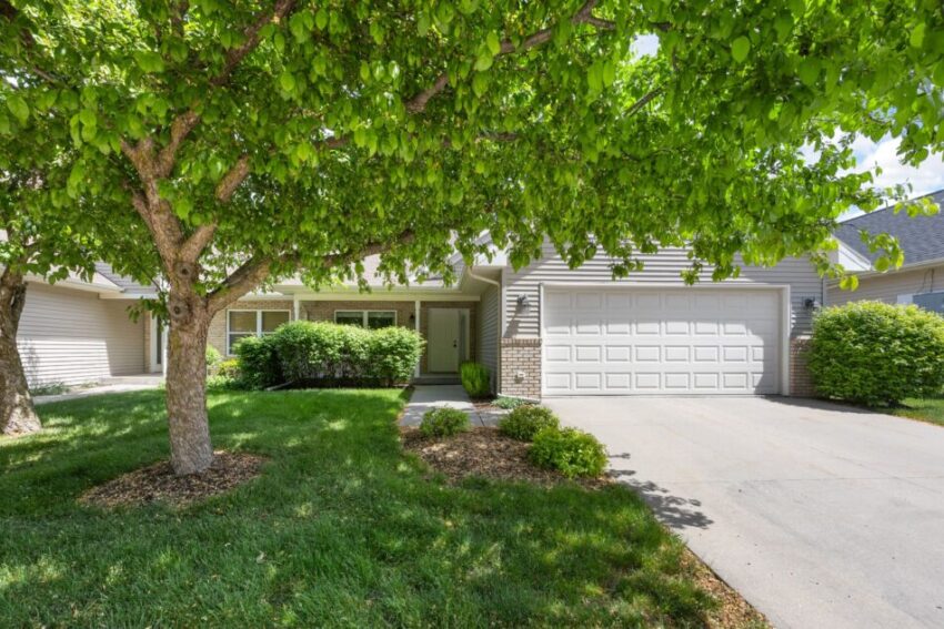 Front view of a house with a garage and lush green trees.