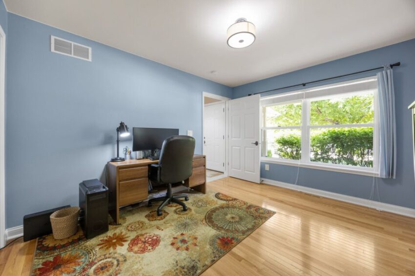 Home office with desk, chair, computer, and large window.