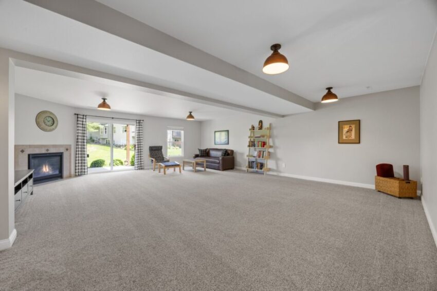 Spacious living room with fireplace, large windows, and carpeted floor.
