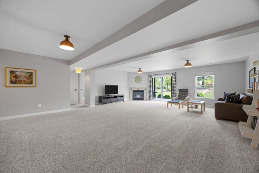 Spacious living room with carpet, sofa, TV, and large windows.