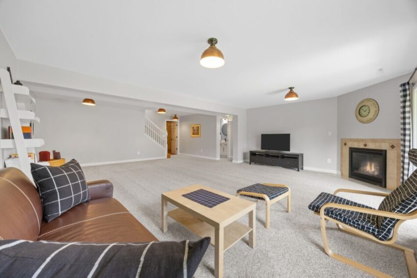 Spacious living room with modern furniture, fireplace, and TV.