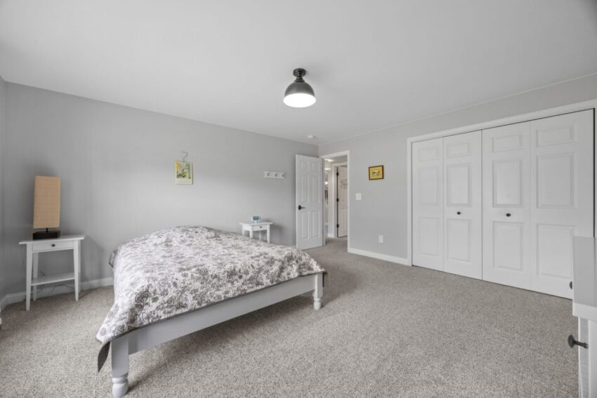 Minimalist bedroom with gray walls, bed, and white closet doors.