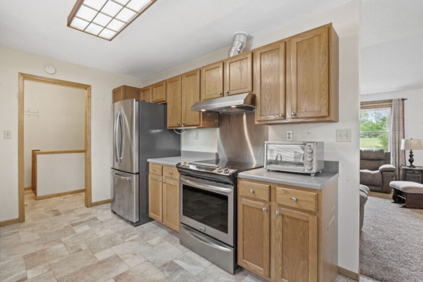 Kitchen with wooden cabinets, stainless steel appliances, and tiled floor.