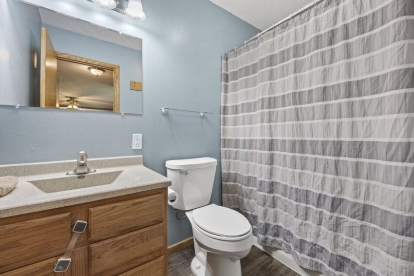 Bathroom with wooden vanity, white toilet, and striped shower curtain.