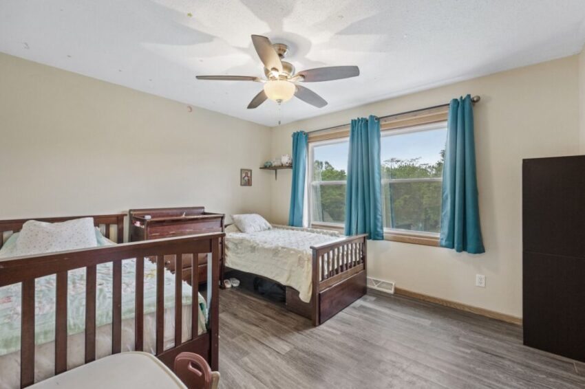 Bedroom with two beds, blue curtains, and a ceiling fan.
