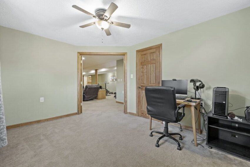 Home office with desk, chair, computer, and ceiling fan.