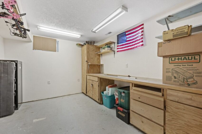 Garage with wooden cabinets, work bench, and overhead lighting.