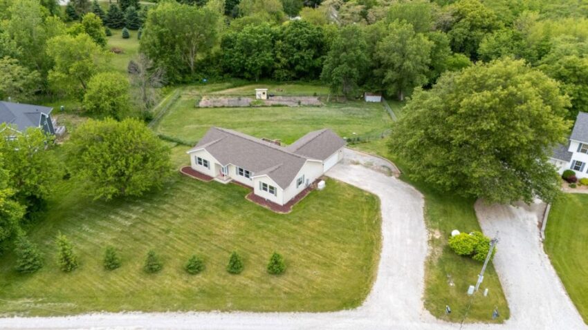 Aerial view of a house with surrounding greenery and driveway.