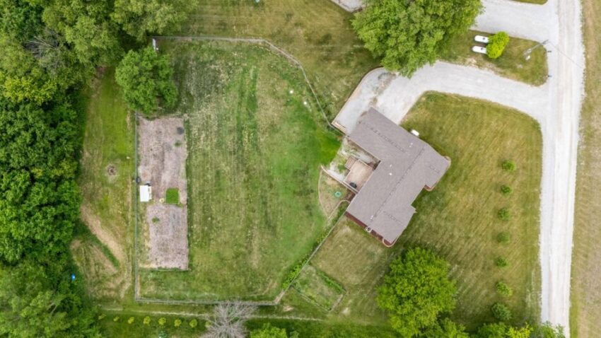 Aerial view of a house with surrounding greenery and driveway.