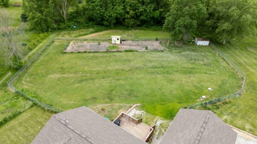 Aerial view of a fenced backyard with a garden and trees.