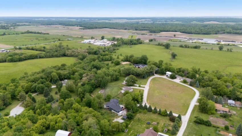 Aerial view of rural landscape with fields, trees, and houses.