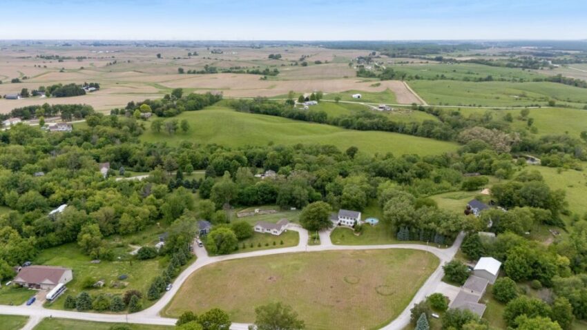 Aerial view of rural landscape with fields, trees, and scattered houses.