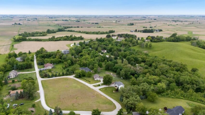 Aerial view of rural landscape with fields, trees, and houses.