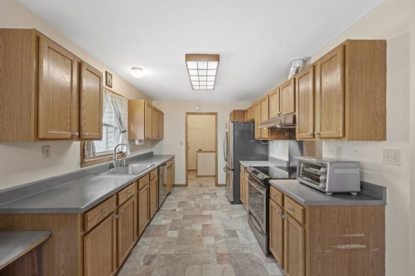 Spacious kitchen with wooden cabinets, stainless steel appliances, and tiled floor.