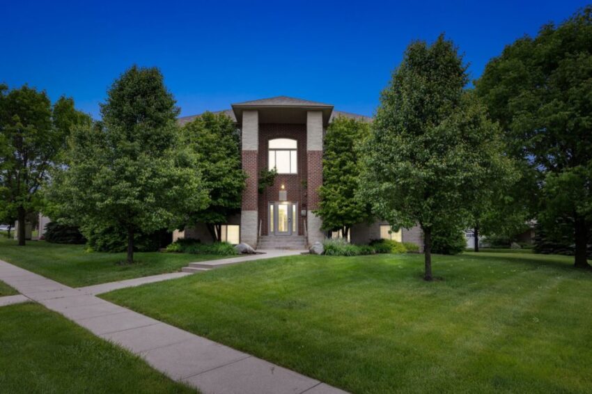 Two-story brick building surrounded by trees and grass under a clear blue sky.